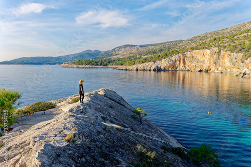 A woman wearing a hat admires the beach Malo Zarace in the Adriatic coast on Hvar island, Croatia. Travel and summer holidays concept.