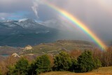 rainbow touching the ground between the mountains