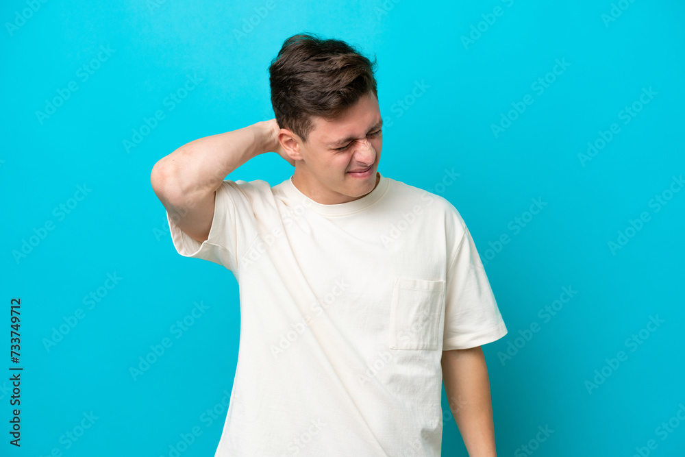 Young handsome Brazilian man isolated on blue background with neckache