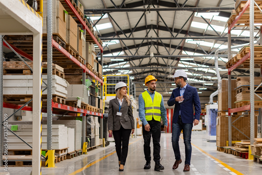 Engineers walking with foreman in modern industrial factory, talking about new production project or investment. Team management in manufacturing facility. Engineers walking with foreman in modern industrial factory, talking about new production project or investment. Team management in manufacturing facility.