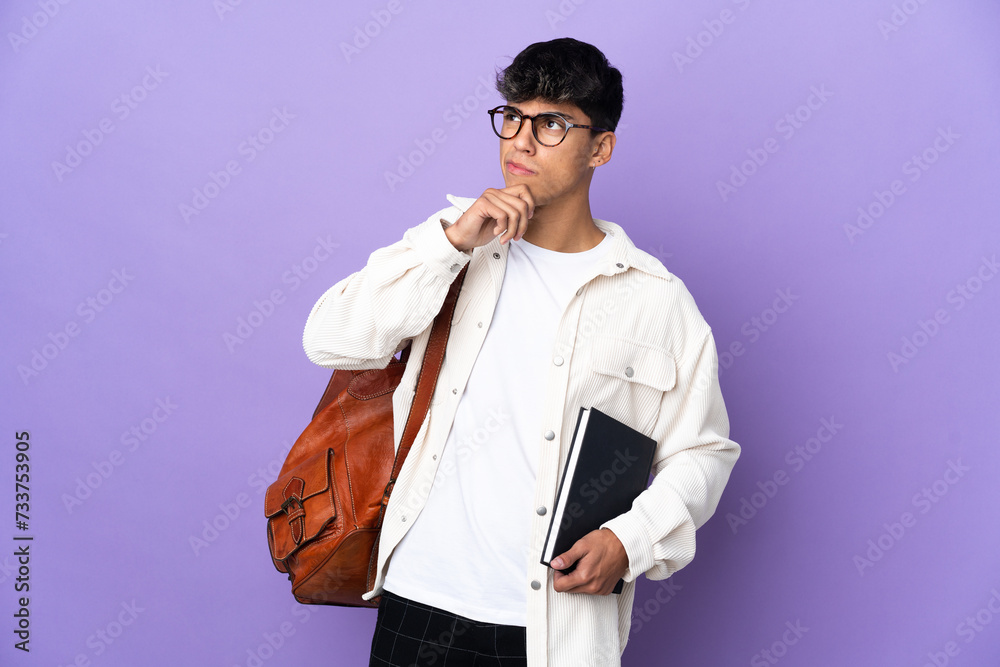 Young student man over isolated purple background and looking up Young student man over isolated purple background and looking up