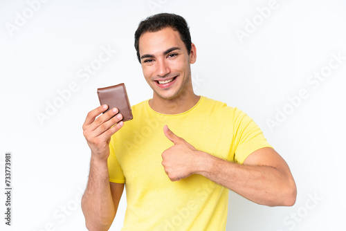Young caucasian man holding a wallet isolated on white background with thumbs up because something good has happened
