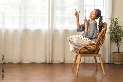 Portrait of smiling happy and relax beauty asian woman pointing finger on banner copyspace for advertising and introduce new product, customer, recommend, positive, present at home