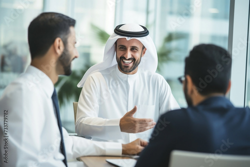 Saudi successful business people in traditional Kandura meeting and talking at office desk. Saudi, Emirati, Arab businessman. photo