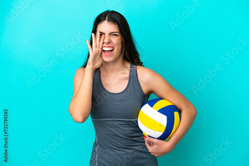 Young Italian woman playing volleyball isolated on blue background shouting with mouth wide open photo