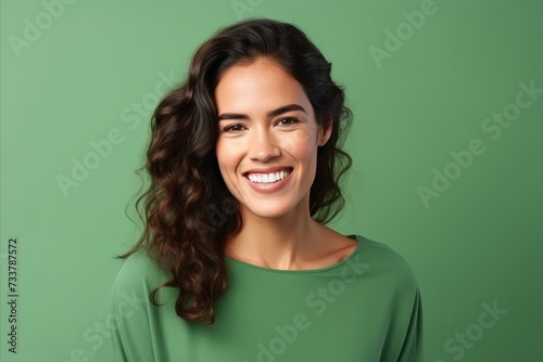 Portrait of happy smiling young woman in green sweater, over green background