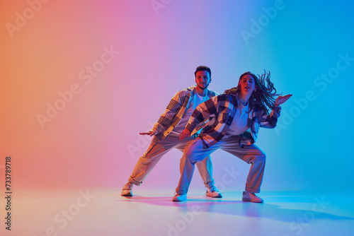 Full length portrait of coordinated dance pair dancing in neon lighting. Fluid movement. Harmony in motion, people expressive energy. Concept of music, rhythm, dance battles. Dynamic gel portrait © Lustre