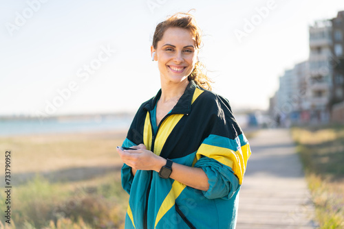 Young woman at outdoors wearing sport wear and listening music with phone © luismolinero