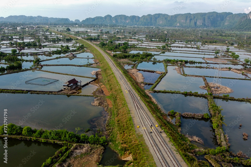 Fototapeta premium View of railway tracks and rice fields in the countryside in, Indonesia