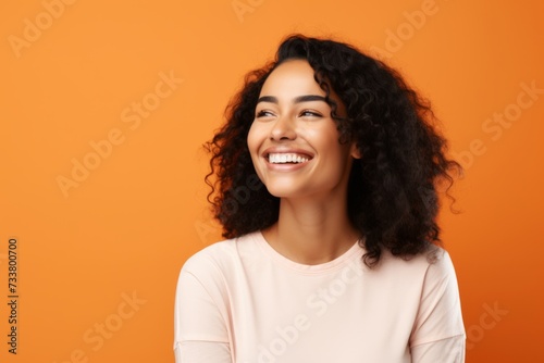 happy african american woman with curly hair over orange studio background
