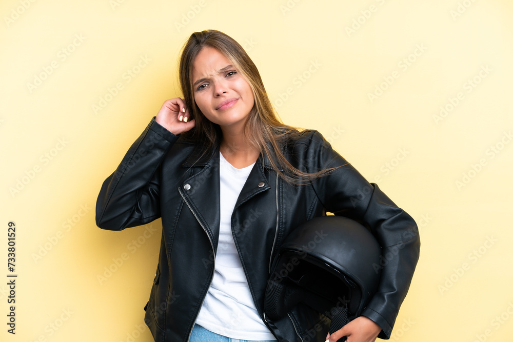 Young caucasian woman with a motorcycle helmet isolated on yellow background having doubts Young caucasian woman with a motorcycle helmet isolated on yellow background having doubts