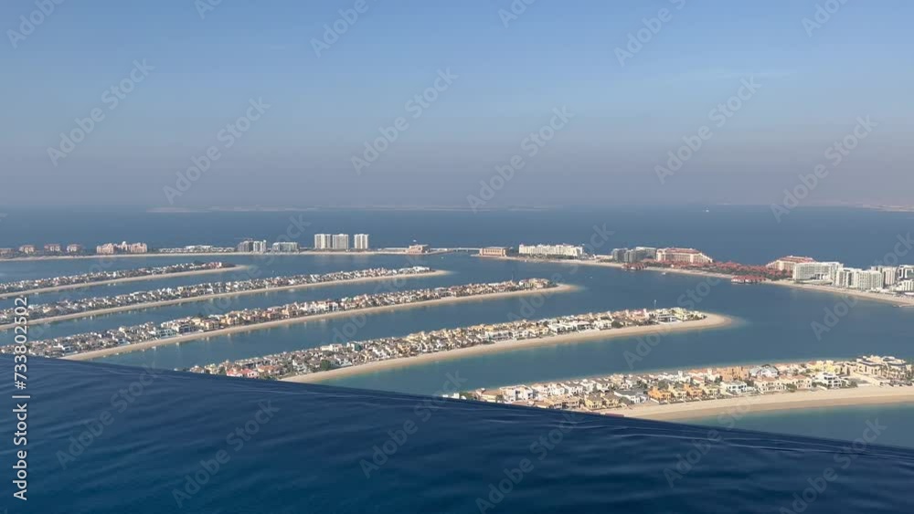 Aerial view of Dubai Palm Jumeirah island, United Arab Emirates. Tourists relaxing in AURA sky pool bar, the world's highest 360 degree infinity pool on Palm Jumeirah overlooking Dubai Marina skyline