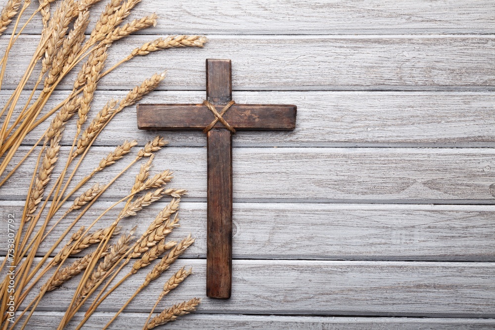 Wood cross and golden wheat on desk