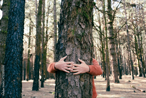 Nature lover hugging trunk tree with green musk in tropical woods forest. Green natural background. Concept of people love nature and protect from deforestation or pollution or climate change