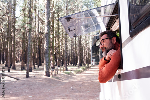 One man enjoying the view outside the window of a motorhome camper van enjoying vanlife and alternative travel vehicle vacation holiday. Freedom. Nomadic lifestyle people fulltimers. Free parking van