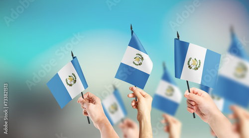 Fototapeta Naklejka Na Ścianę i Meble -  A group of people are holding small flags of Guatemala in their hands.