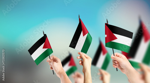 Fototapeta Naklejka Na Ścianę i Meble -  A group of people are holding small flags of Jordan in their hands.