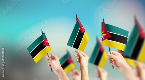 Fototapeta Naklejka Na Ścianę i Meble -  A group of people are holding small flags of Mozambique in their hands.