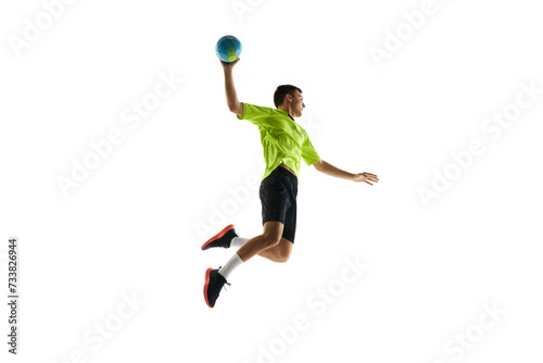 Dynamic image of young man in uniform, handball player in motion during game, practicing, jumping with ball against white studio background. Concept of professional sport, tournament, competition © master1305