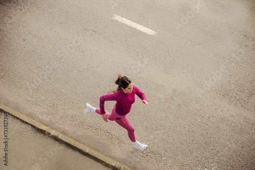 Top view of a fast female runner running on driveway.