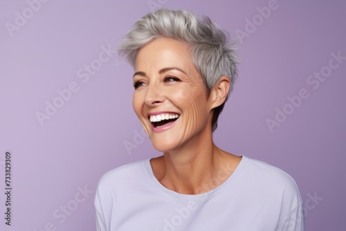 Cheerful middle aged woman. Portrait of beautiful mature woman looking at camera and smiling while standing against purple background