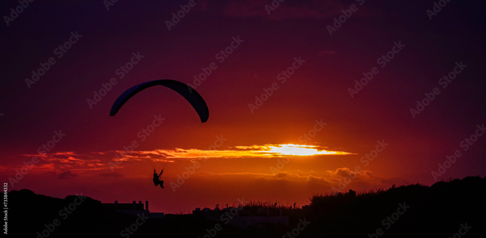 Gleitschirmflug an einer Klippe am Meer in der Nähe von Nazaré bei Sonnenuntergang. Gleitschirmflug an einer Klippe am Meer in der Nähe von Nazaré bei Sonnenuntergang.