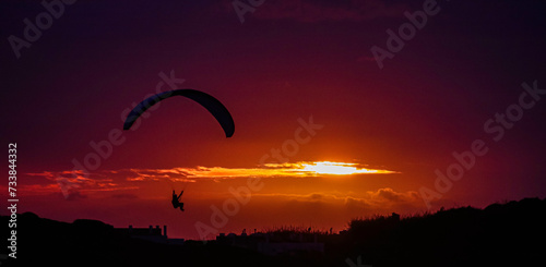 Gleitschirmflug an einer Klippe am Meer in der Nähe von Nazaré bei Sonnenuntergang.