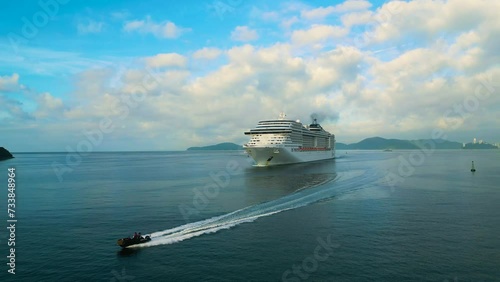 Santos, Brazil, December 2023: Cruise liner sailing. People on the upper deck celebrates vacation. 4K aerial view of shipboard of the cruise ship leaving terminal. Water transportation.
 photo