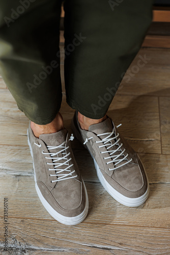 Collection of men's summer shoes. Male legs in beige leather sneakers. Men's classic shoes.