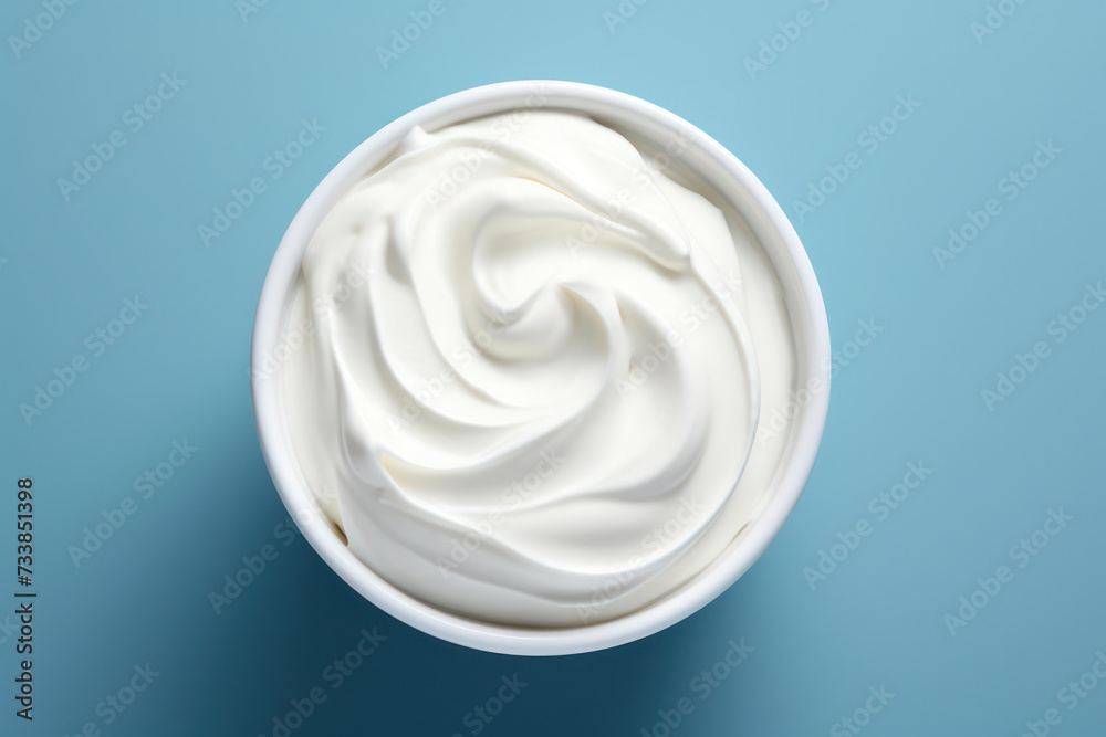 Creamy White Yogurt Swirl: A Deliciously Light and Healthy Homemade Snack, a Tempting Dairy Delight on a Smooth Blue Background. Creamy White Yogurt Swirl: A Deliciously Light and Healthy Homemade Snack, a Tempting Dairy Delight on a Smooth Blue Background.