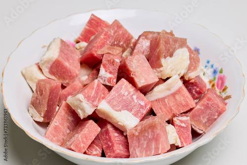 Pork cut into pieces in a bowl to be cooked.