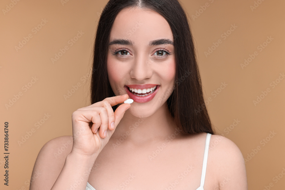 Beautiful young woman with vitamin pill on beige background Beautiful young woman with vitamin pill on beige background