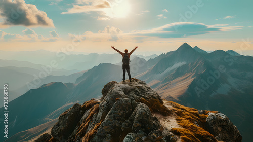 Man standing on top of a mountain with his arms raised photo
