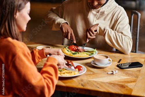 Fototapeta Naklejka Na Ścianę i Meble -  diverse couple enjoying breakfast with delicious omelette,  and sausages near cups of coffee
