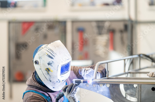 a man wearing a welding helmet is welding a piece of metal in a factory