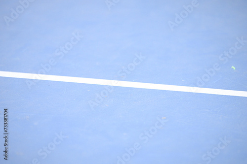 A close up photo of blue tennis court with white line