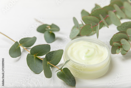 Jar of moisturizing cosmetic cream for face  hands and body with eucalyptus leaves on a white wooden background. Natural organic product. Beauty and spa concept. Body care. Space for text.Copy space.