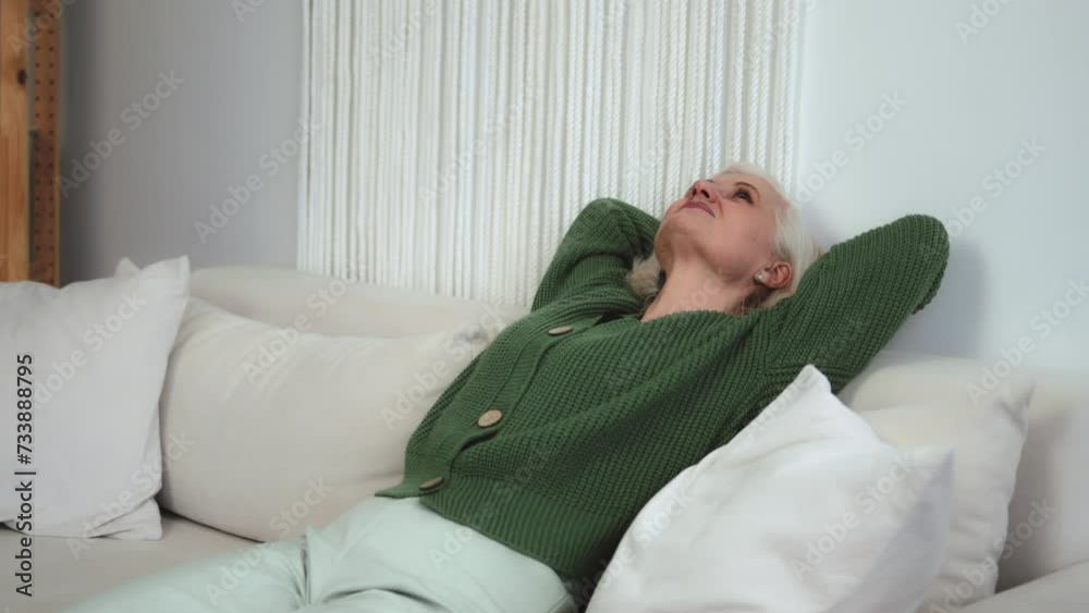 Attractive mature old granny woman resting on couch taking deep breath of fresh air holding hands behind head, healthy calm lady relaxing on comfortable sofa napping feel stress free at home Attractive mature old granny woman resting on couch taking deep breath of fresh air holding hands behind head, healthy calm lady relaxing on comfortable sofa napping feel stress free at home
