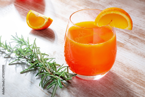 Fresh orange drink with rosemary on a wooden background, a cocktail or a mocktail