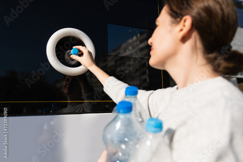 Woman uses a self service machine to receive used plastic bottles and cans on a city street.. photo