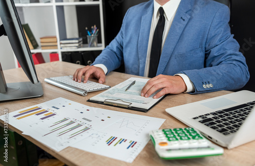 Business man in suit calculate annual profit by duty with finance document computrer and calculator