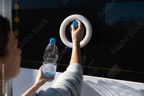 Woman uses a self service machine to receive used plastic bottles and cans on a city street.. photo