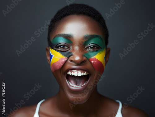 Beautiful girl as Euphoric National South Africa Team Fan with painted country flag colors face excited laughing and screaming straight at the camera. Active sports fans movement and human emotions.