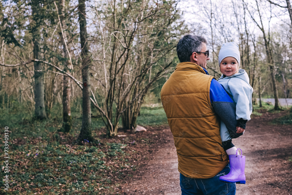 Father holding little girl while walking in spring park. Father holding little girl while walking in spring park.