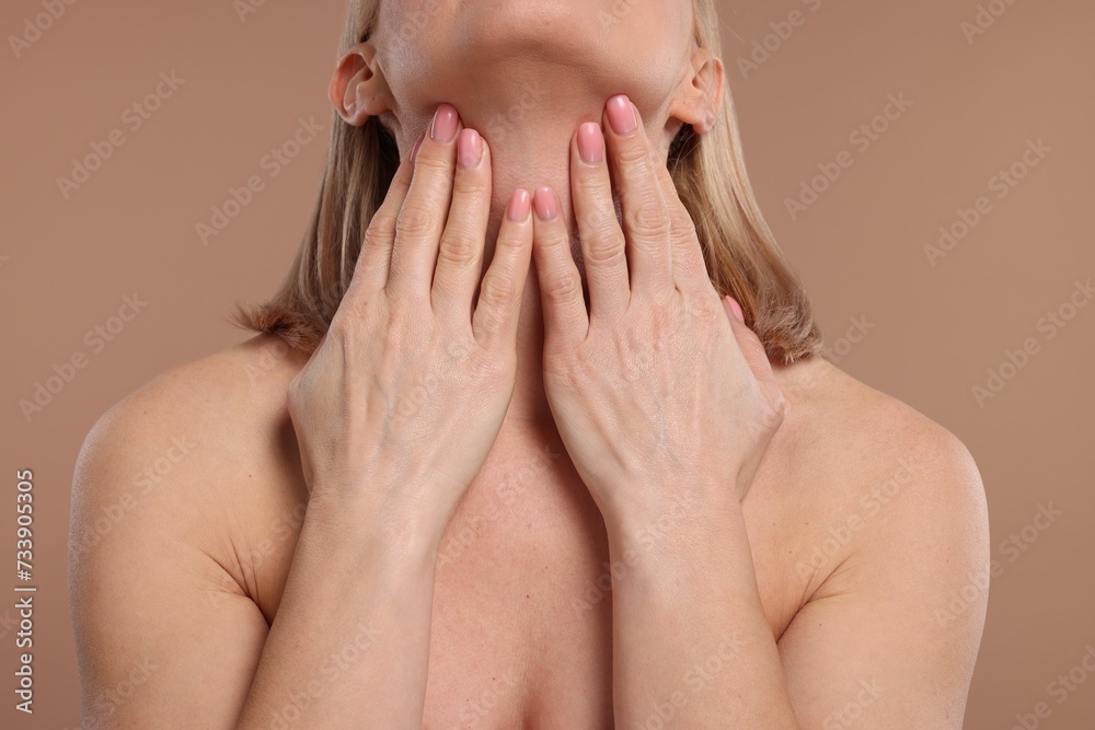 Fototapeta premium Beautiful woman touching her neck on beige background, closeup
