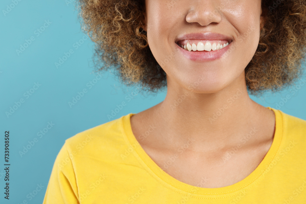 Woman with clean teeth smiling on light blue background, closeup Woman with clean teeth smiling on light blue background, closeup