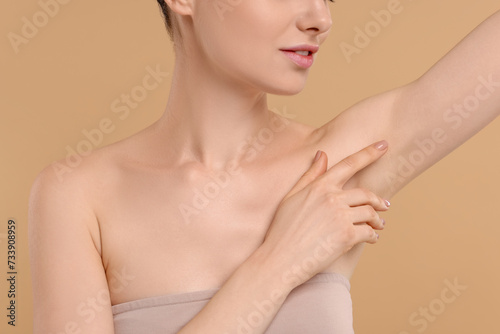Woman showing armpit with smooth clean skin on beige background, closeup