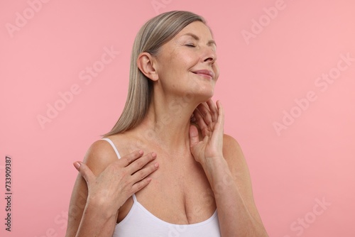 Beautiful woman touching her neck on pink background
