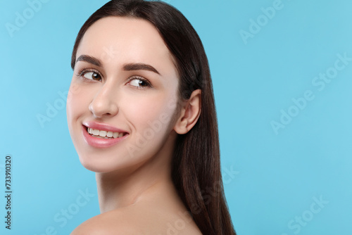 Portrait of beautiful young woman on light blue background. Space for text