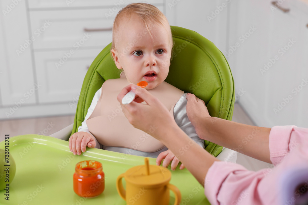 Mother feeding her cute little baby with healthy food at home Mother feeding her cute little baby with healthy food at home